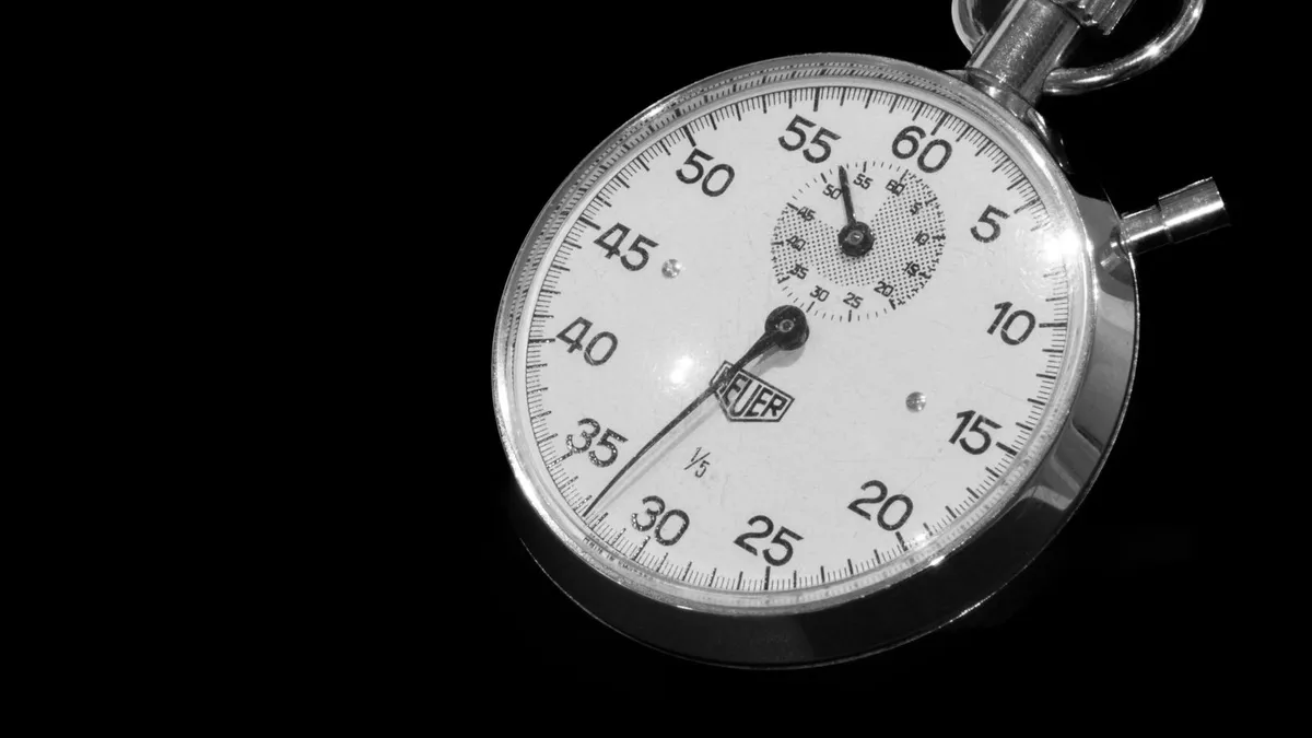 Stopwatch on a desk beside a laptop timing a quick online loan application