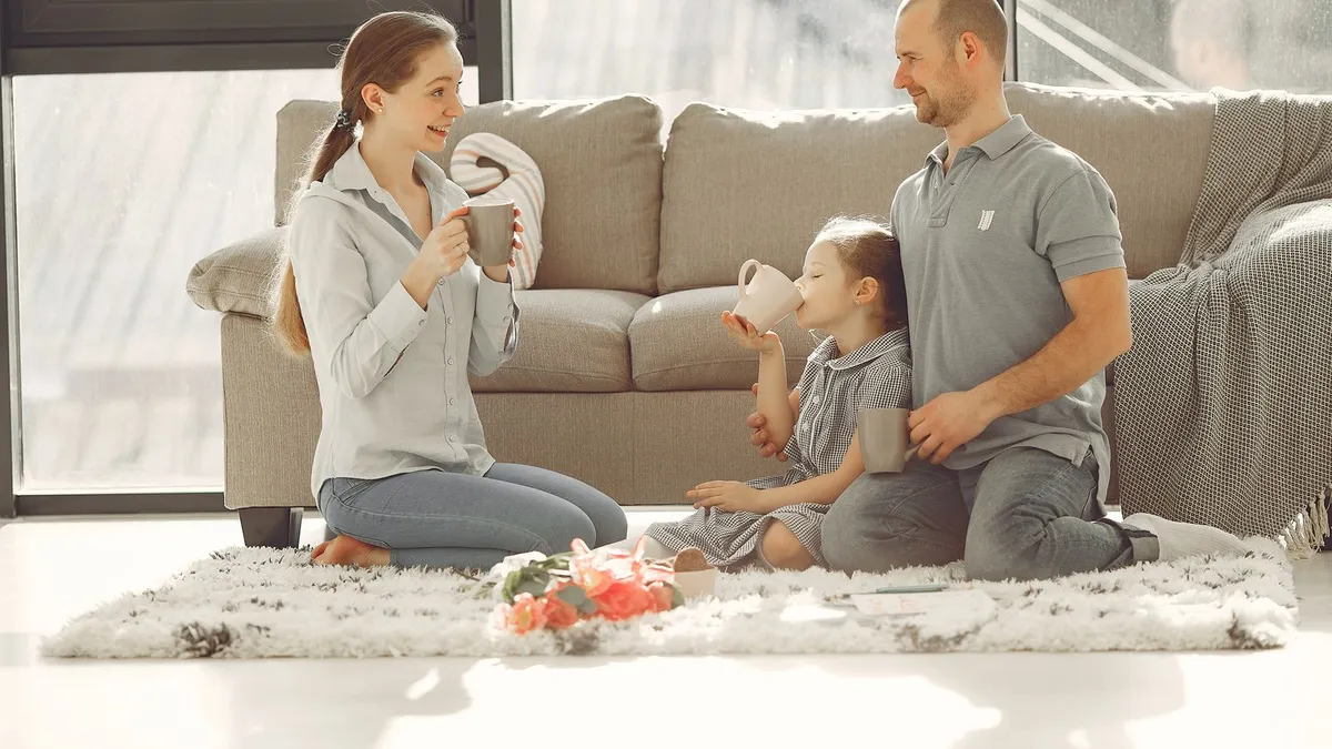 Family at home on a weekend morning while a parent checks a loan e-transfer on a laptop
